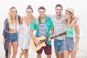 Group of friends standing on the beach with a guitar