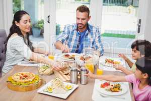 Family having food while sitting at dining table