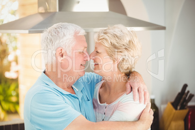 Senior couple embracing while touching nose in kitchen