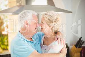 Senior couple embracing while touching nose in kitchen