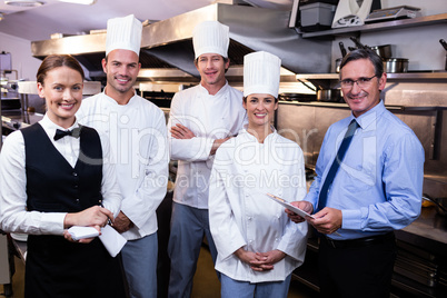 Happy restaurant team standing together in commercial kitchen
