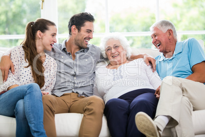 Smiling family discussing while sitting on sofa