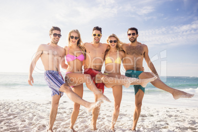 Smiling friends standing in line with leg up