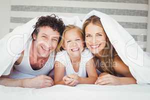Portrait of happy family covered with duvet