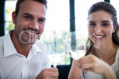 Portrait of couple toasting wine glasses at dining table