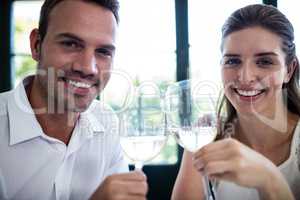 Portrait of couple toasting wine glasses at dining table