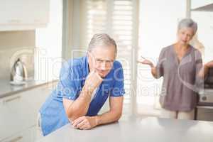 Senior man with woman arguing in background
