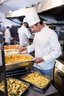Chef standing at serving trays of pasta