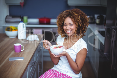 Happy young woman having breakfast in kitchen