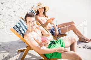 Portrait of young couple sitting on armchair with cocktail drink