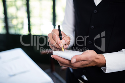 Close-up of waiter taking an order wearing a waistcoat