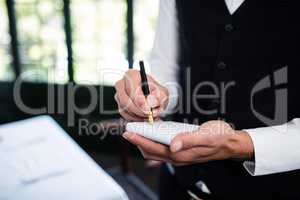 Close-up of waiter taking an order wearing a waistcoat