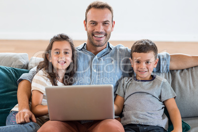 Father sitting on sofa with son and daughter