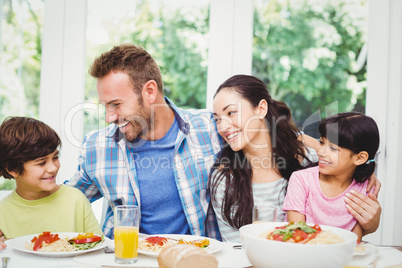 Smiling family with arm around while sitting at dining table
