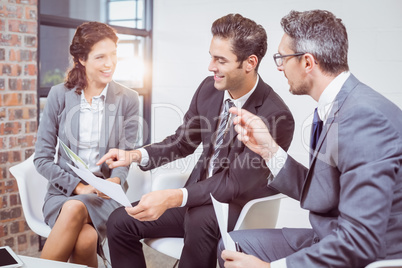 Happy business people holding documents while sitting on chairs