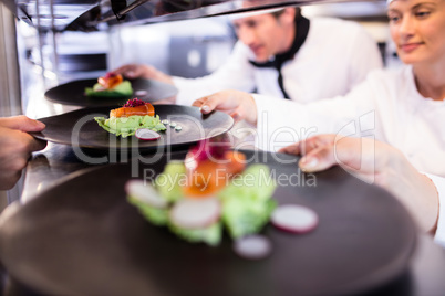 Chef handing appetizer plate through order station