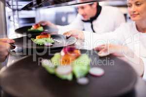 Chef handing appetizer plate through order station