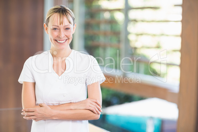 Happy female masseur with arms crossed at health spa