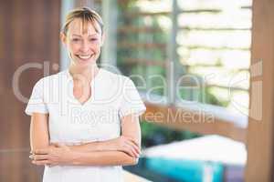 Happy female masseur with arms crossed at health spa