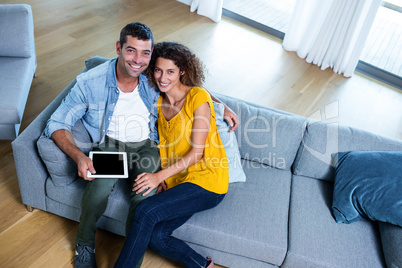 Portrait young couple sitting on sofa and using digital tablet