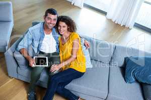 Portrait young couple sitting on sofa and using digital tablet