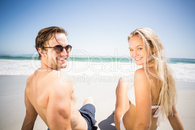 Happy couple sitting on the beach