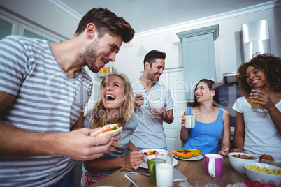 Cheerful friends having breakfast at table