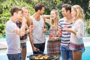 Happy friends preparing barbecue near pool