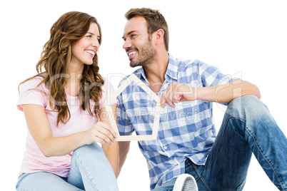 Young couple holding house shaped popsicle sticks