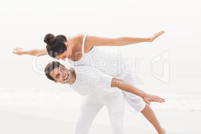 Man giving a piggy back to woman on the beach