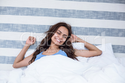 Smiling woman stretching on bed