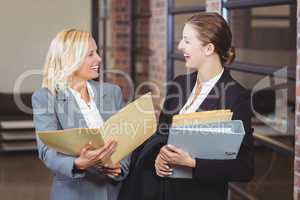 Smiling businesswomen holding documents