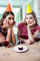 Portrait of sad friends sitting at table during birthday party