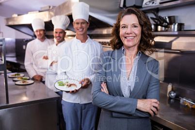 Restaurant manager posing in front of team of chefs