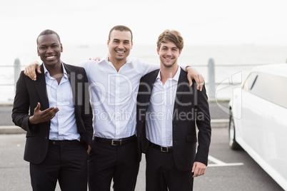 Handsome men posing next to a limousine