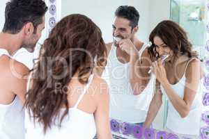 Couple brushing teeth while looking in mirror