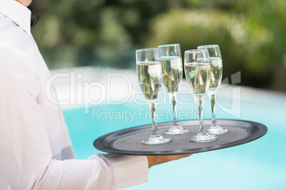 Waiter carrying champagne flutes on tray