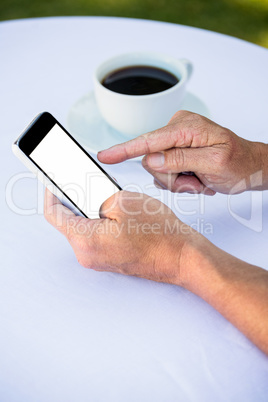 Close up of masculine hands using smartphone and having coffee