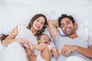 High angle view of couple lying on bed with baby