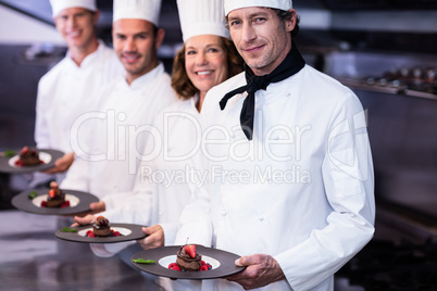 Portrait of happy chefs presenting their dessert plates