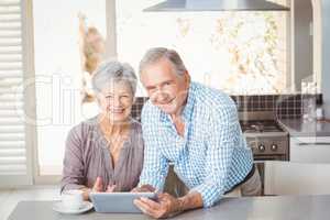 Portrait of happy senior couple with tablet