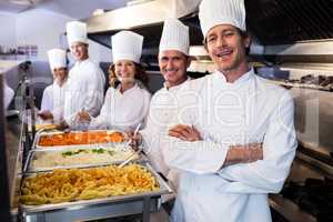 Chefs standing at serving trays of pasta