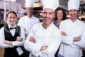 Happy restaurant team standing together with arms crossed in com