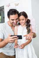 Smiling father using smartphone with daughter