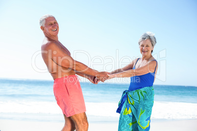 Cute mature couple holding hands on the beach