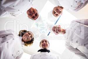 Portrait of chefs team standing in a circle wearing uniforms