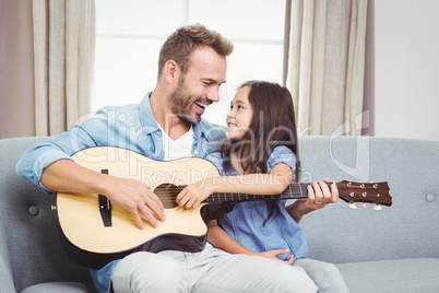 Man playing guitar with daughter at home