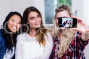Young female friends taking selfie with smart phone