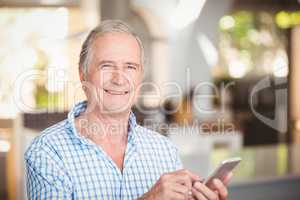 Portrait of happy senior man using mobile phone