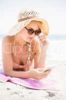 Pretty woman in bikini and sunglasses using mobile phone on the